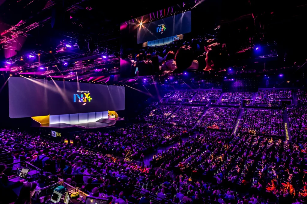 Audience at Google Cloud Next '26 event looking at the main stage screen in a purple-lit arena
